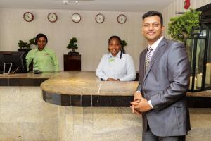 a man in a suit standing in front of a counter at De Rembrandt Classic Hotel in Ikeja