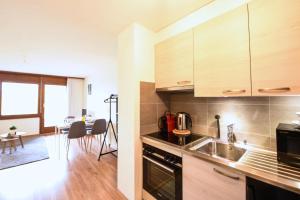 a kitchen with wooden cabinets and a dining room at Charming and comfortable studio ideally located in Saillon in Saillon