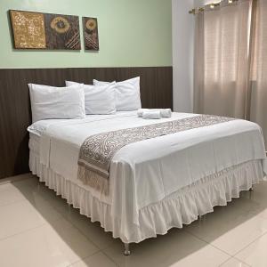 a bedroom with a large bed with white sheets and pillows at Hotel Rio Verde in Dianópolis