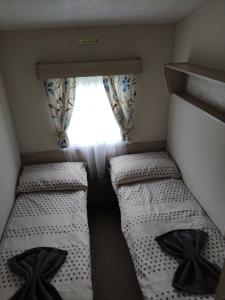 two beds in a small room with a window at Lovely Static 8 Bed Caravanat at Billing Aquadrome in Great Billing