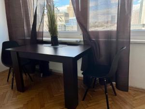 a black table with a plant on it in front of a window at Wspólna Apartment in Warsaw