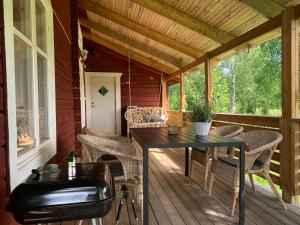 a screened porch with a table and wicker chairs at Bogärdan, cozy cabin by the Luleå River in Harads
