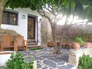 un patio con bancos y un árbol frente a un edificio en Casa rural El Olivo en Aracena