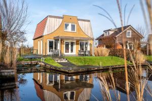 a house with a reflection in the water at Recreatiepark Tusken de Marren in Akkrum