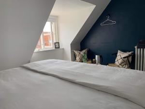 a bedroom with a large white bed with a blue wall at Room in a Danish cottage with garden view, 10 min to CPH in Gentofte