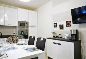 a white kitchen with a table and chairs and a microwave at VENTUNO - Modern Apartment - Country & Lake in Lovere