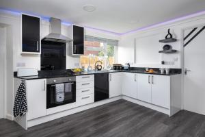 a kitchen with white cabinets and black appliances at Four Oaks House in Carlisle