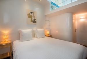 巴黎的住宿－Makom Pereire，一间卧室配有一张带两盏灯的大型白色床。