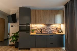 a kitchen with gray cabinets and a brick wall at Bison Apartamenty in Białystok