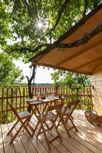 une table et des chaises en bois sur une terrasse en bois dans l'établissement Cabanes de la Grande Noe, à Les Épasses