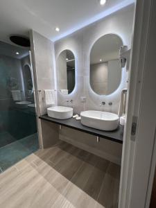 La salle de bains est pourvue de 2 lavabos et de 2 miroirs. dans l'établissement Pegasus Hotel, à Sassari