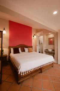 a bedroom with a large bed with a red wall at Hotel Casa Guivá in Oaxaca City