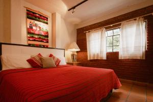 a bedroom with a red bed and a brick wall at Hotel Casa Guivá in Oaxaca City