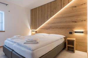 een slaapkamer met een groot wit bed en een houten muur bij Appartamento Campanile Basso in San Lorenzo in Banale
