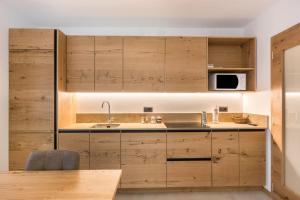 een keuken met houten kasten en een wastafel bij Appartamento Campanile Basso in San Lorenzo in Banale