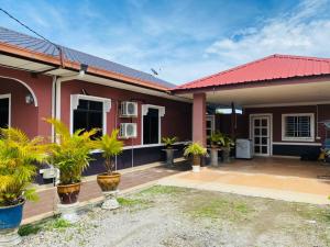 a house with a red roof and plants in front at ALOR SENARI HOMESTAY PRIVATE POOL in Pantai Cenang
