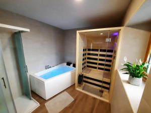 a bathroom with a bath tub and a glass door at Apartments Hlapi with SPA in Kobarid