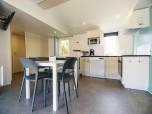 a kitchen with a table and chairs in a room at Camping Paradis 4 étoiles Au Port de L'Houmeau - La Rochelle in LʼHoumeau