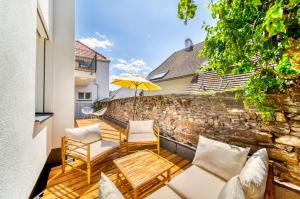 un patio con 2 sillas y una sombrilla en Smile Apartments Burggasse, en Krems an der Donau