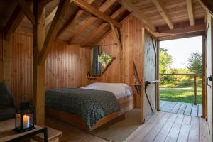 - une chambre avec un lit dans une cabane en bois dans l'établissement Cabanes de la Grande Noe, à Les Épasses