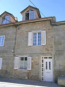 an old stone building with white doors and windows at Antia - Casita de piedra en Lariño in Carnota