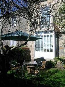 a table and chairs and an umbrella in a yard at Antia - Casita de piedra en Lariño in Carnota +2 photos