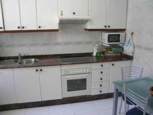 a kitchen with white cabinets and a sink and a microwave at Antia - Casita de piedra en Lariño in Carnota