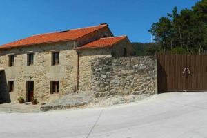 ein Steingebäude mit einem Tor und einem Zaun in der Unterkunft Casa Crina Casa restaurada con finca grande in Outes