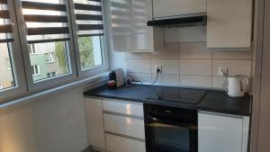 a kitchen with white cabinets and a black counter top at Apartament Jakubek II in Polkowice