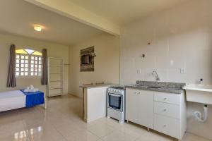uma cozinha com armários brancos e um lavatório em Pousada Carolina em Florianópolis