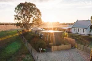 a tiny house in a field with the sun setting at Church Lane Accommodation, Milawa. in Milawa
