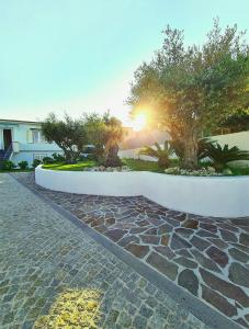 a stone walk way with trees and the sun in the background at Villa Olea in Procida in Procida