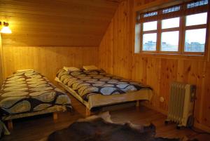 two beds in a room with wooden walls and windows at Tatra Holiday House in Tatra