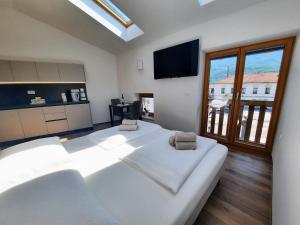 Schlafzimmer mit einem großen weißen Bett und einem großen Fenster in der Unterkunft Apartments Hlapi with SPA in Kobarid