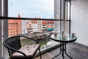 a table and chair on a balcony with a view of a city at Uroczy Apartament No1 w ,, SERCU Starego Miasta Wyspa Spichrzów,, in Gdańsk