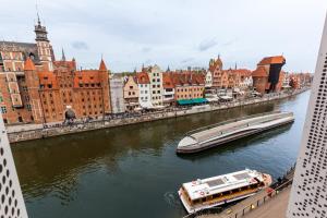 łódź płynąca rzeką w mieście w obiekcie Uroczy Apartament No1 w ,, SERCU Starego Miasta Wyspa Spichrzów,, w Gdańsku