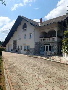 a large white building with a balcony and a patio at Studio Apartman Brletić in Tounj