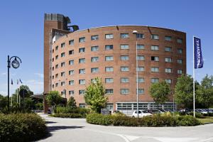 a large brick building with cars parked in a parking lot at Novotel Venezia Mestre Castellana in Mestre