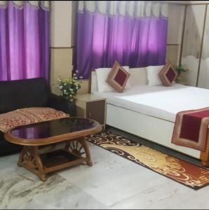 ein Wohnzimmer mit einem Bett und einem Couchtisch in der Unterkunft Hotel Aditya Palace in Ranchi
