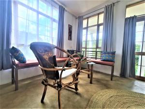 a room with a chair and a table and windows at Holiday cottage by the river, Arusha in Arusha