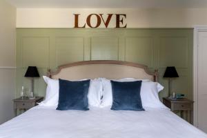 Una cama con sábanas blancas y almohadas azules con un cartel de alove encima. en Number 40, en Kingsbridge