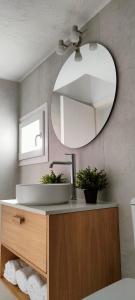 ein Bad mit einem Waschbecken und einem Wandspiegel in der Unterkunft Kelly's Urban Apartment in Elounda
