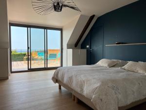 une chambre avec un grand lit et une grande fenêtre dans l'établissement Le Refuge Marin - Gîte familial au bord de mer, à Lamballe