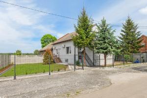 a white house with trees in front of a fence at Verona in Kąty Rybackie