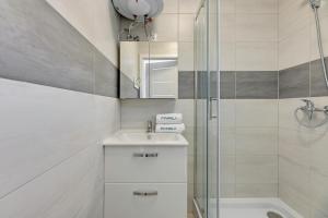 a white bathroom with a sink and a shower at Verona in Kąty Rybackie