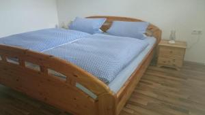 ein Holzbett mit blauer Bettwäsche und einem Nachttisch in der Unterkunft Ferienwohnung Piller in Hohenau