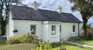 een wit huis met een zwart dak bij Kathleen's Carrowkeel Cottage in Sligo