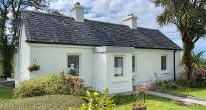 uma casa branca com um telhado preto em Kathleen's Carrowkeel Cottage em Sligo