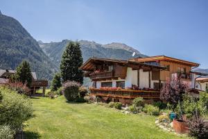 a house in a field with mountains in the background at Gästehaus Waltraud in Längenfeld