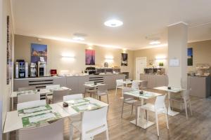 un ristorante con tavoli bianchi e sedie bianche di Green Class Hotel Gran Torino a Torino